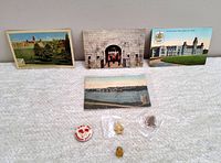 Photo showing four vintage Royal Military College postcards and four lapel pins on light surface.