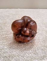 Hand-carved vintage wooden sculpture of a Weeping Buddha figure, shown from a side angle highlighting the details of the pose and wood grain.