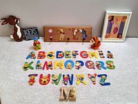 Full assortment of Winnie the Pooh children's toys and nursery decor including wooden Rabbit key rack, wooden Pooh key rack, alphabet puzzle, Pooh figurine, Tigger plush, and framed Piglet artwork.
