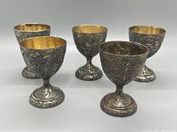 Front view of 4 silver plate repousse goblets showing detailed exterior floral pattern and gold-tone inside