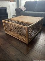 Front angled view of square wicker rattan coffee table showing woven top and lattice sides with magazine slot.