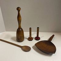 Five primitive wooden kitchen tools: mallet, two candle holders, two spoons on white background