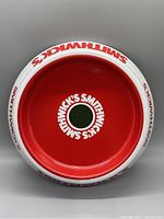 Top-down photo showing the bright red interior of the ashtray with Smithwick's white text and green circle center.