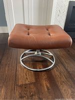 Front view of the vintage leather ottoman showing brown leather seat and chrome base.