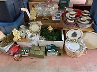 Full view of assorted Christmas plate sets, glassware, figurines, greenery, and boxed decor