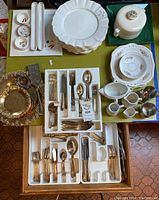 Overview of the flatware trays, plates, and serving pieces on a green table.
