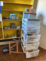 White plastic storage drawers stacked with crafting materials and miniatures on yellow shelving