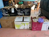 Photo of assorted stemware boxes containing multiple types of glasses including wine and margarita glasses shown on top of the boxes.
