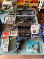 Overview of all items laid out including the Dremel tool in carrying case, Super Engraver, rotary tool accessory set, glue tool, router attachment, and drill pump in box.