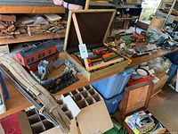 Overview of model train accessories on a wooden table, including buildings, track, and other parts.