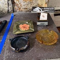 Three ashtrays and one pipe carving kit displayed on a surface