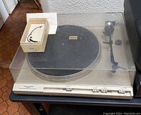 Full view of the Realistic turntable with transparent dust cover and Garrard stylus gauge box on top.