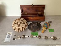 Overall view of the lot showing all four items: basket, wooden jar lid, painted crocodile, and teak box.