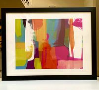 Framed abstract art print featuring bright overlapping brush strokes in multiple colors within a black frame and white matting.