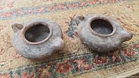 Two small round Israeli clay oil lamps sitting on a rug, showing top and front sides with spouts and filling holes visible.