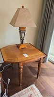 Full view of octagonal drop leaf side table with lamp on top for scale and setting. Shows solid wood legs with carved detail and veneer table top.