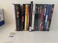 Photo showing 13 DVDs standing upright with their spine labels visible.