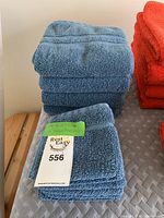 Stack of blue face and hand towels with folded towel in front showing texture and ribbed band. Rest Easy brand tag visible.