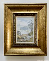 Framed watercolor artwork titled 'A Dorset Cove' showing entire framed piece on wall.