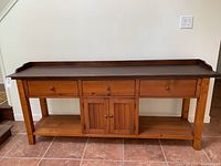 Front view of pine sideboard showing three drawers above cabinet doors and open shelves below