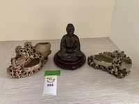 Overview of two soapstone vessels and seated Buddha statue on wooden base