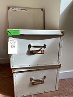 Two white faux leather storage boxes stacked, with visible metal handles and label holders, brown corner detail, and tag indicating lot 525