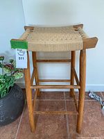 Front view of the vintage teak stool with hand-strung woven seat showing overall condition and wooden frame.