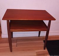 Front view of mid-century modern teak side table showing rectangular top and magazine shelf.