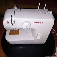 Front angled view of white Singer Start sewing machine with stitch selector and presser foot in focus.