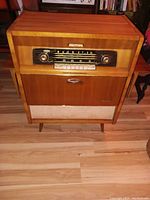 Front view of wooden cabinet console radio with fabric speaker grill and tuning dial