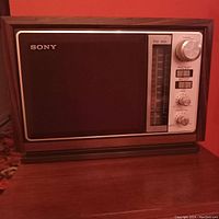 Front view of the vintage Sony ICF-9740W AM/FM tabletop radio with faux wood finish and silver control panel, showing the speaker, tuning scale, and knobs.