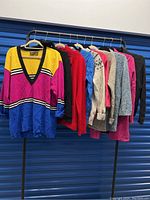 All 10 women's sweaters and cardigans hanging on rack showing variety of colors and styles.