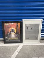 Both poster frames side by side; black frame on left and white frame on right, showing size difference and packaging.