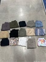 Overview of all 15 pairs of women's petite pants and shorts laid out on floor, various colors and styles