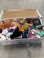 Box of assorted vintage Beanie Babies plush toys showing many animal characters with tags visible