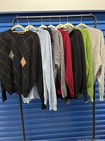 Seven men's XL cashmere sweaters in varied colors and patterns hung on a rack.