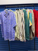 Eight men's cotton button down shirts hanging on a clothes rack, shown side view
