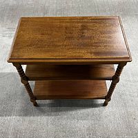 Top view of Vintage Imperial wood side table showing rectangular top with turned spindle legs and two lower shelves, medium brown wood finish.