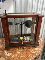 Front and overall view of the vintage balance scale in a wooden and glass case showing the scale components and casing.
