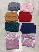Eight folded pairs of women's pull-on pants and leggings, showing a variety of colors and textures.