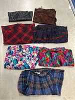 All 7 skirts laid out on the floor showing variety of patterns and colors including floral, plaid, striped, faux leather and paisley.