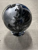 Front-side view of black and silver globe showing Asia and Australia region, mounted on silver-tone base.