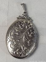 Front view of oval locket showing hand-engraved floral scrollwork