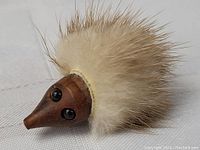 Close-up image showing the teak wood carved hedgehog face with black eyes and cream-colored fur quills behind.