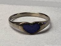 Close-up of sterling silver ring with blue heart-shaped lapis lazuli on white background.