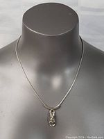 Front view of sterling silver necklace with unique pendant on a display bust.