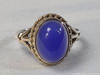 Front view showing the large oval cabochon blue stone with twisted rope bezel setting and split shank band.