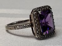 Side view of vintage sterling silver amethyst ring showing the rectangular purple center stone with clear stones on band and halo setting.
