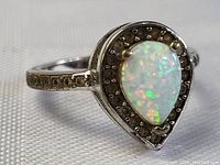 Side angle view showing pear-shaped opal with decorative setting and patterned band.