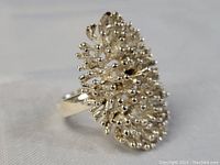 Close-up view of the silver ring from front angle showing the detailed textured dome surface with raised small round forms and irregular branches.